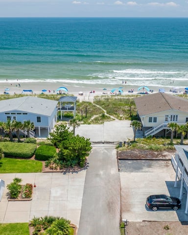 White Adirondack chairs on a beachfront deck overlooking the ocean and pier