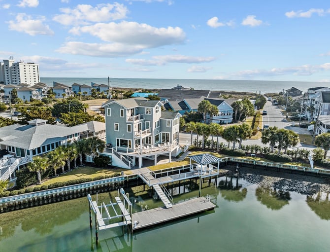Waterfront neighborhood with multi-story homes, docks, and ocean view in background
